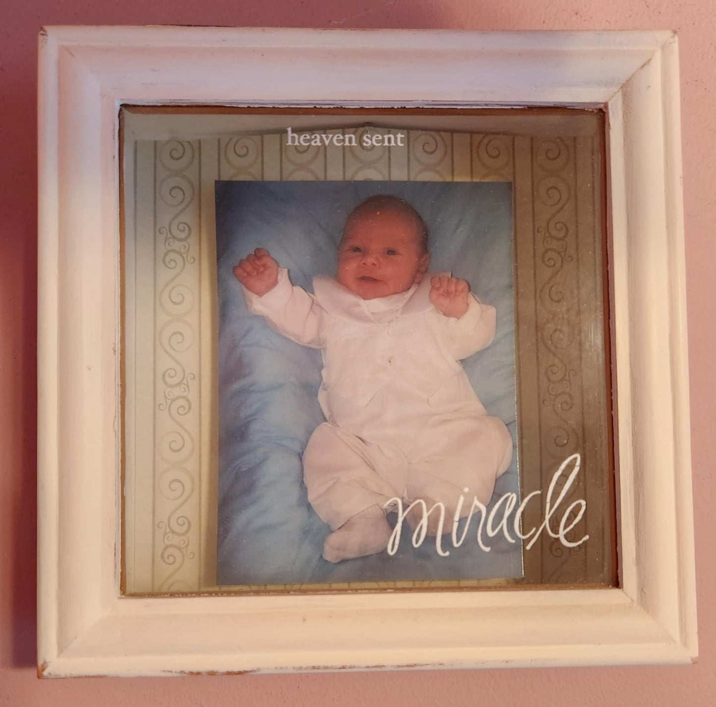 White wood shadow box with a photo of a baby and the wood miracle on the glass in cursive