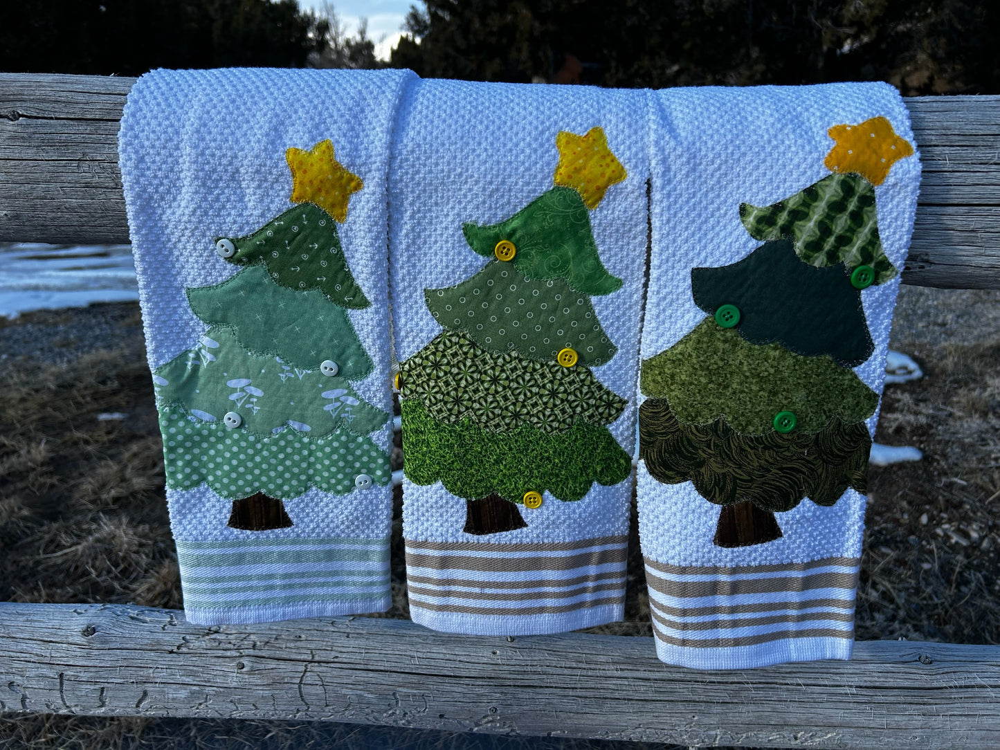Three white hand towels, each tree is green but different patterns. They have a yellow star on to but are all different patterns
