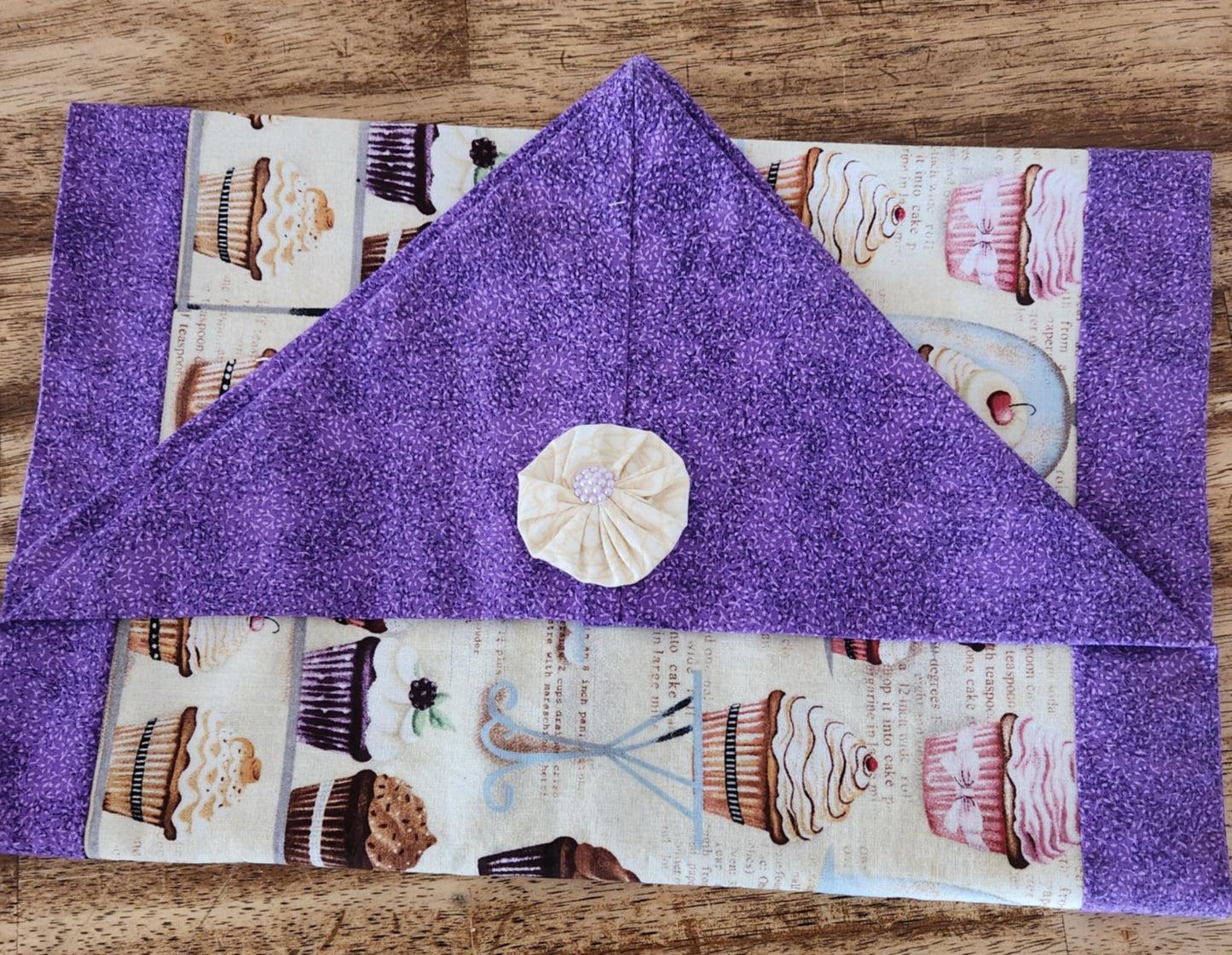 Folded table runner with a purple outside and cupcake pattern inside