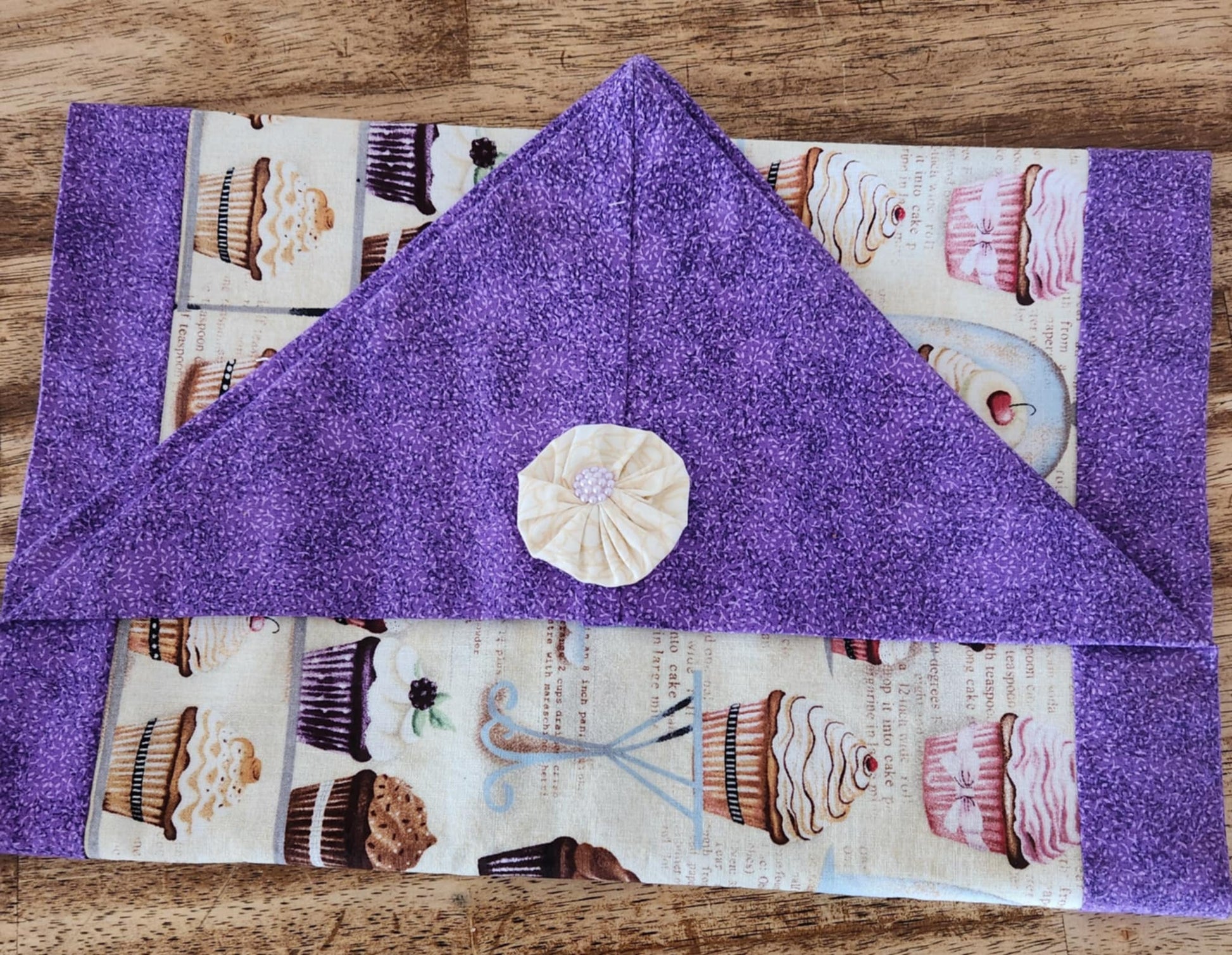 Folded table runner with a purple outside and cupcake pattern inside