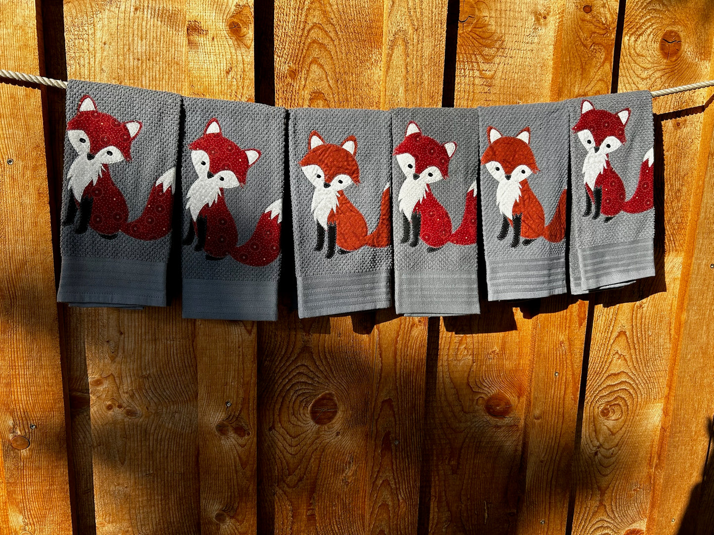 Five Dish towels each one gray. Each fox is red but have different patterns