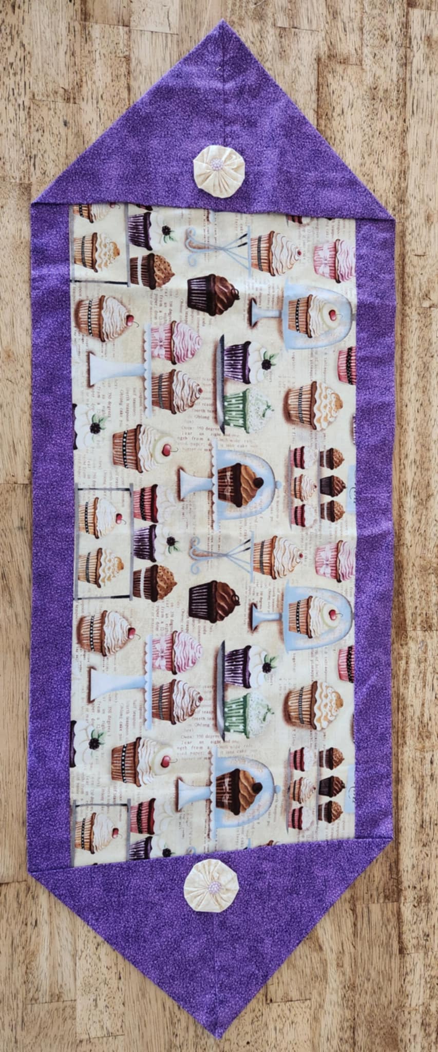 Full table runner with purple fabric on the outside with cupcake pattern fabric on the inside