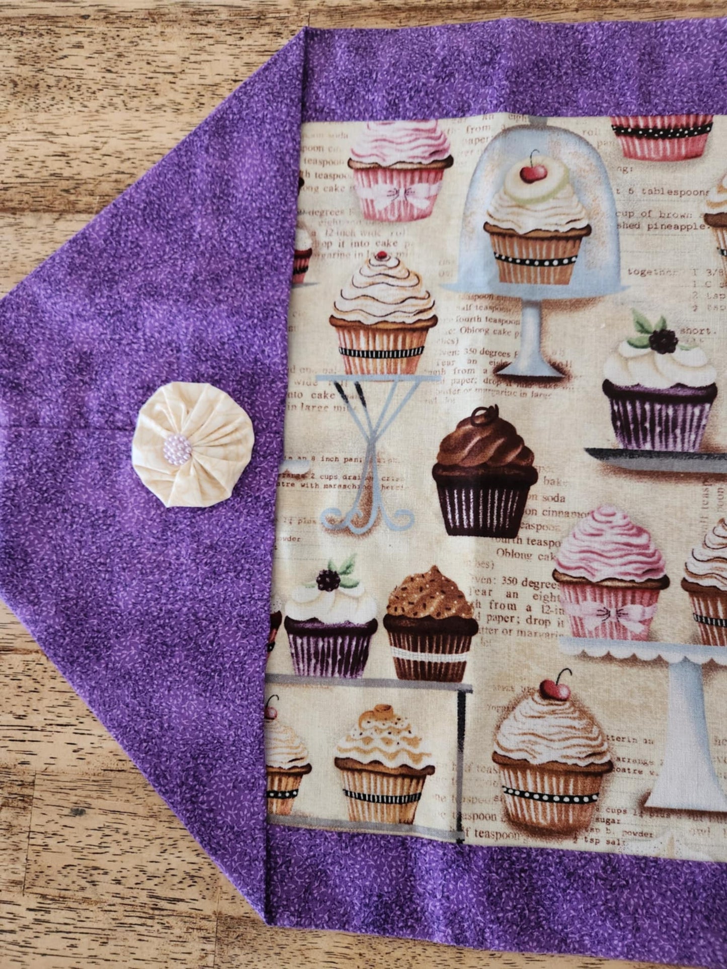 One side of the table runner with purple fabric outside and cupcake pattern fabric inside