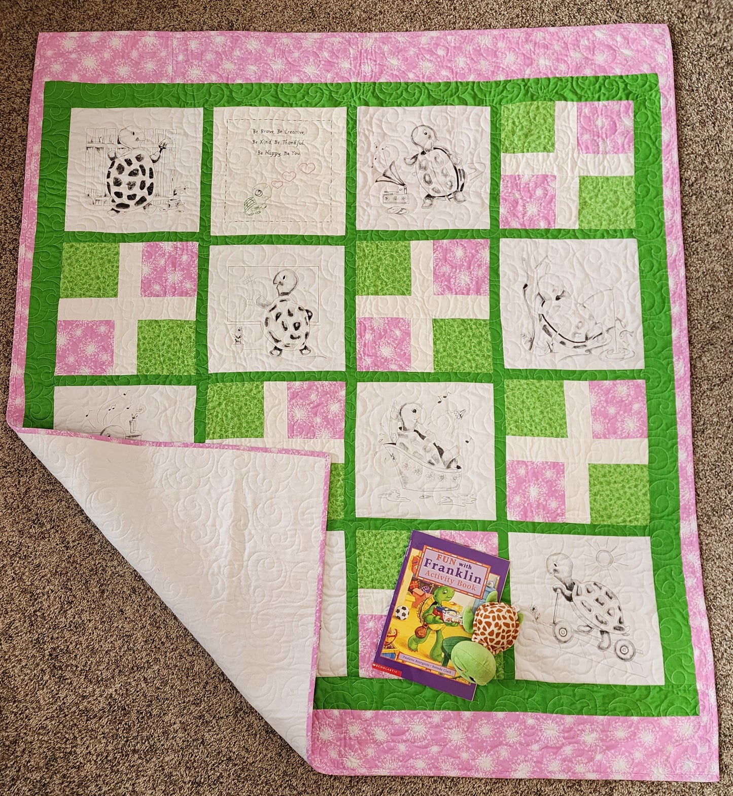 Full Pink and green quilt with turtles doing fun activities with a corner turned up with White flannel on the back. The franklin book and a stuff turtle in the corner