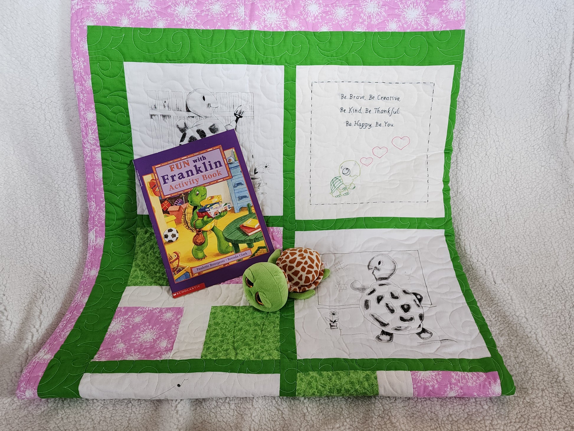 Pink Green and white quilt with a franklin book with a stuff turtle.