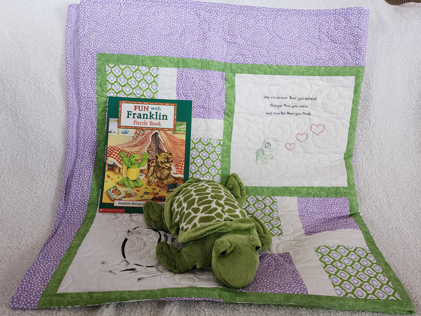 Purple Green and white quilt with a franklin book with a stuff turtle.
