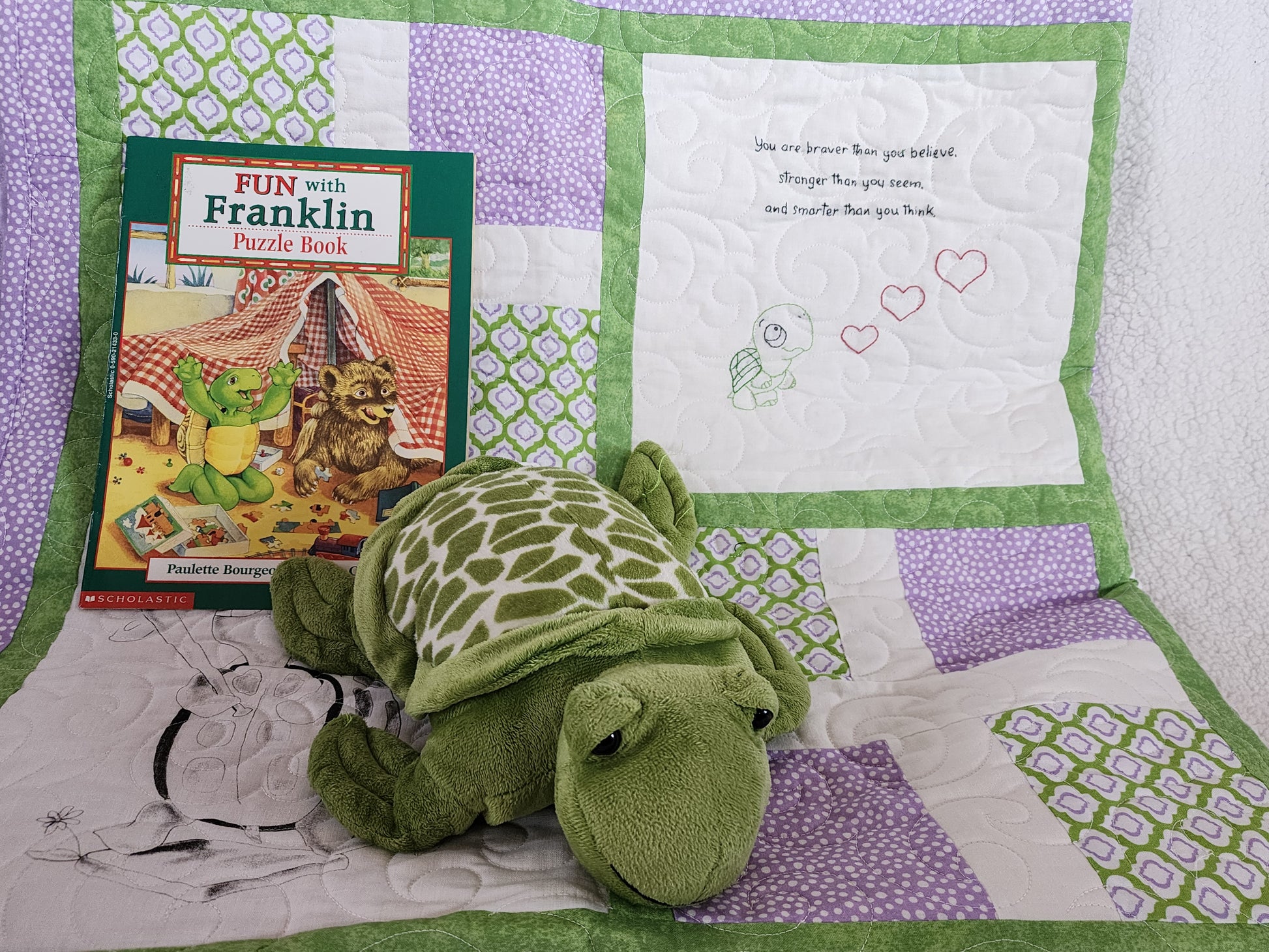 Purple Green and white quilt with a franklin book with a stuff turtle.