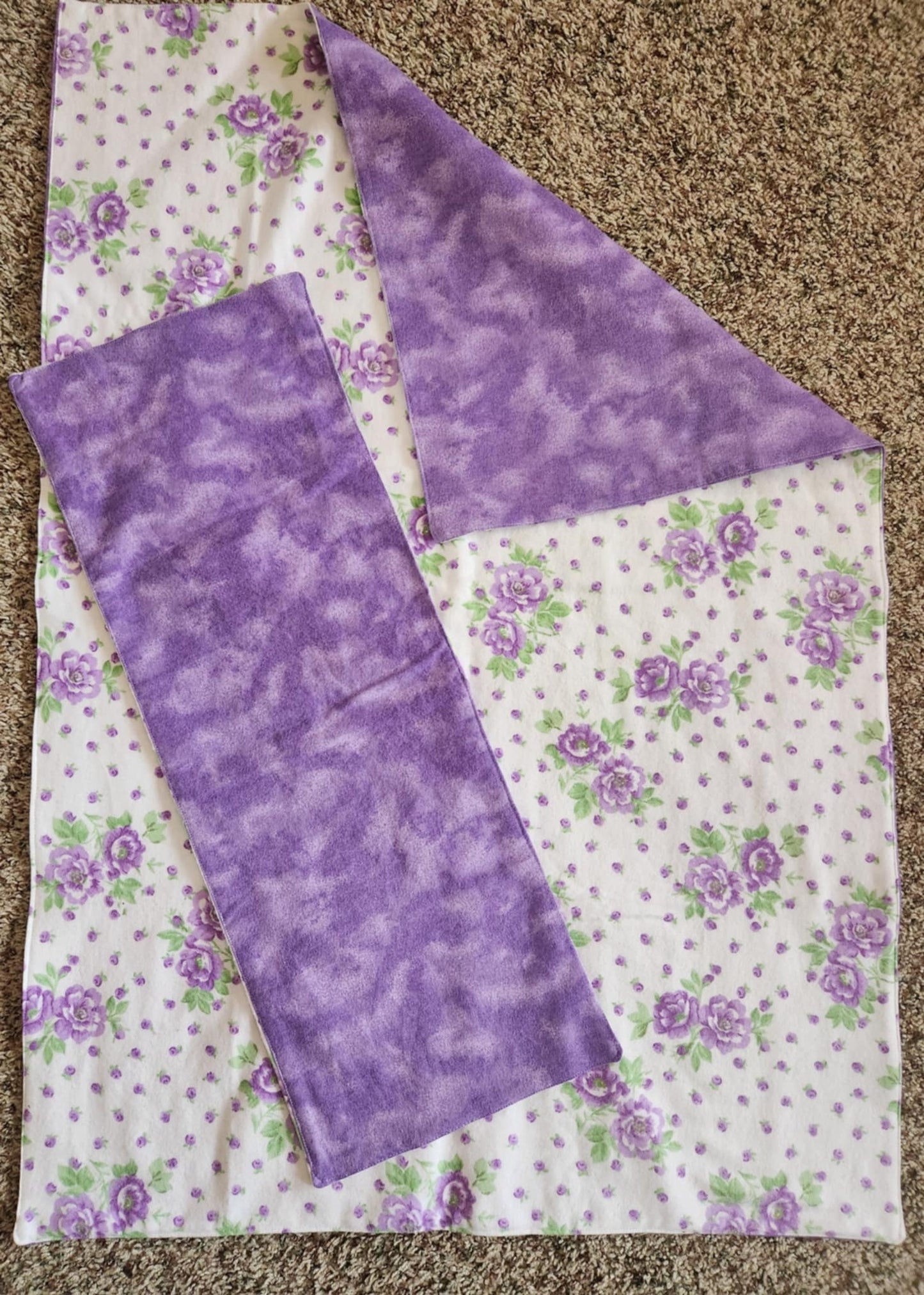 Rectangle Receiving Blanket with purple flowers and purple dots with white background Fleece. With corner turned down showing purple marble fleece. With a Purple marble burp rag on top of the blanket