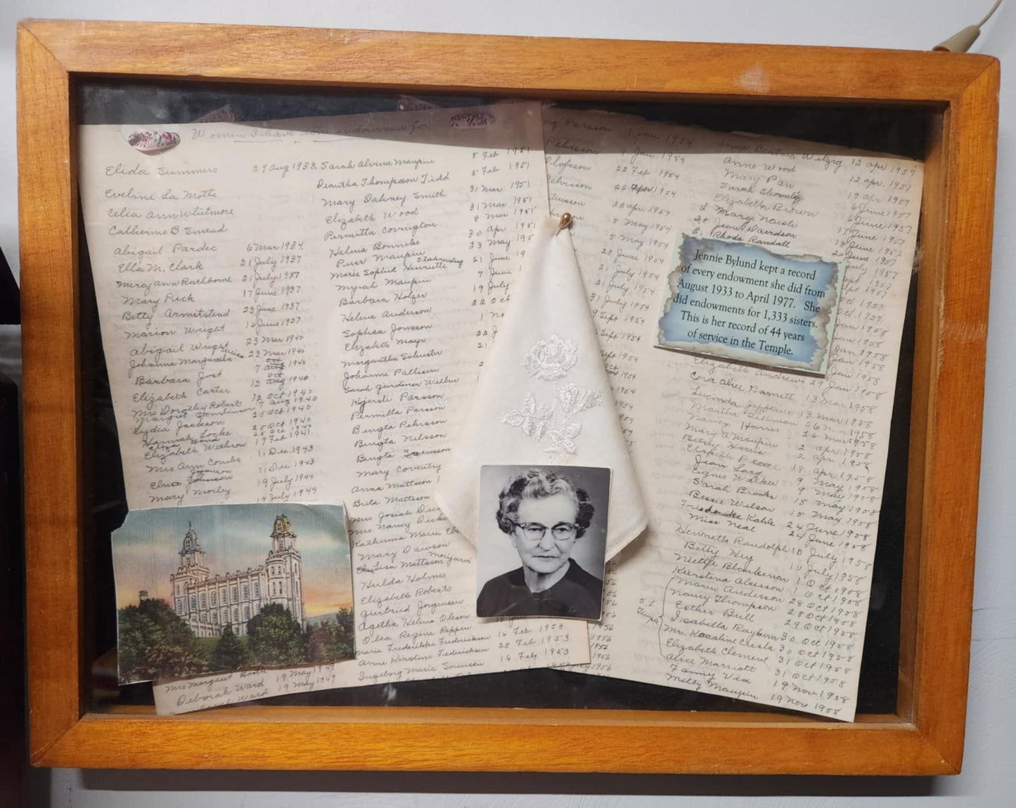 Wood shadow box with two papers with names, a photo of the Manti temple and a black and white photo of a old woman