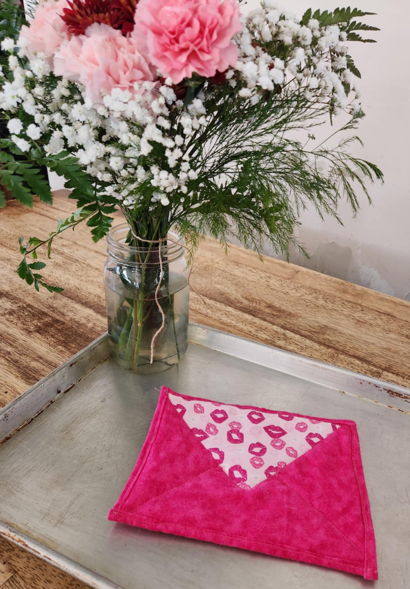 Hot pad shaped like a envelope with light pink background with pink kisses seal flap and the rest a bright pink