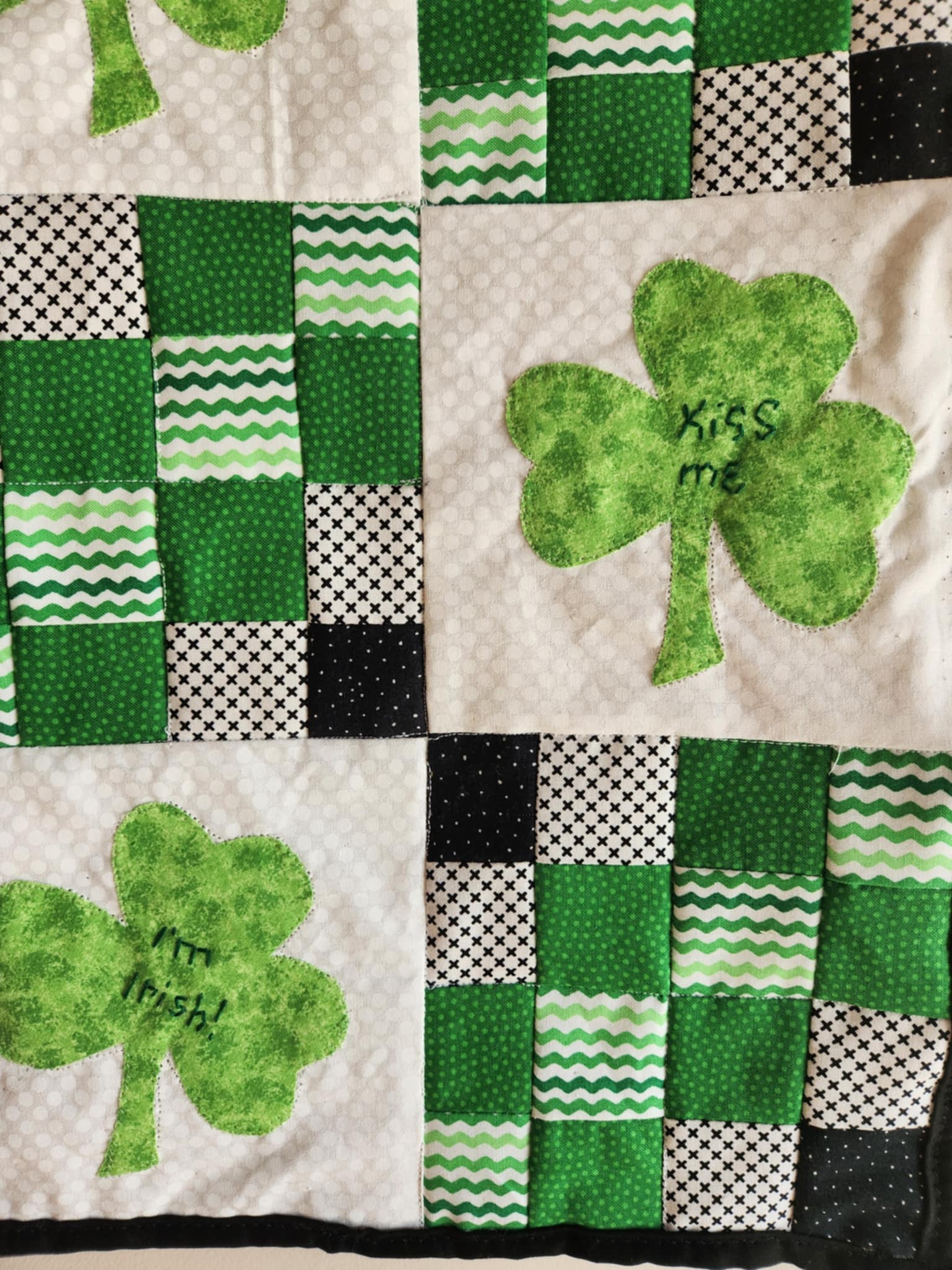 2 green three leaf clovers on white backgrounds. 4 by 4 patchwork squares of green, black and white