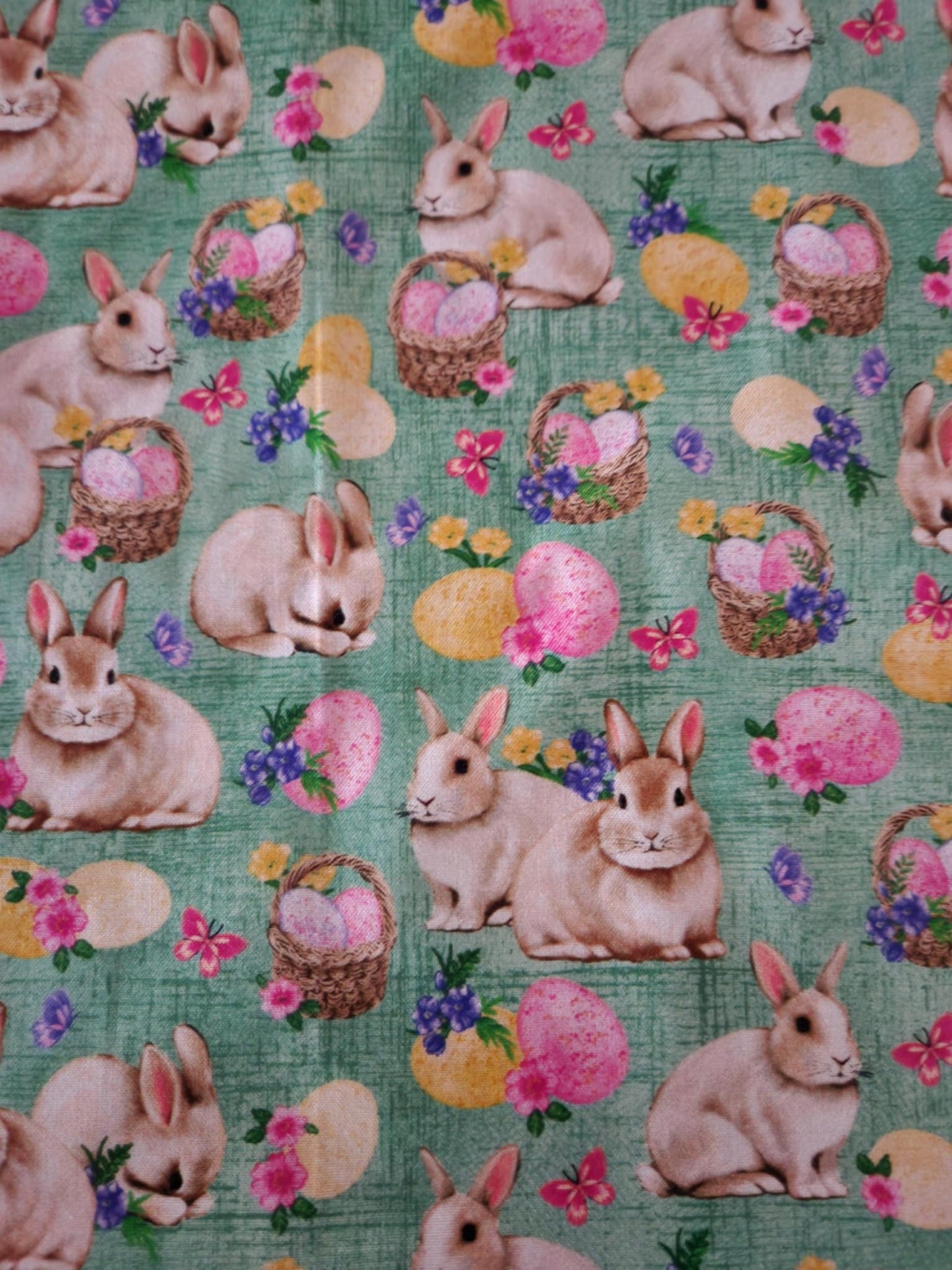A close up table runner with bunnies' with baskets filled with Easter eggs in the middle.