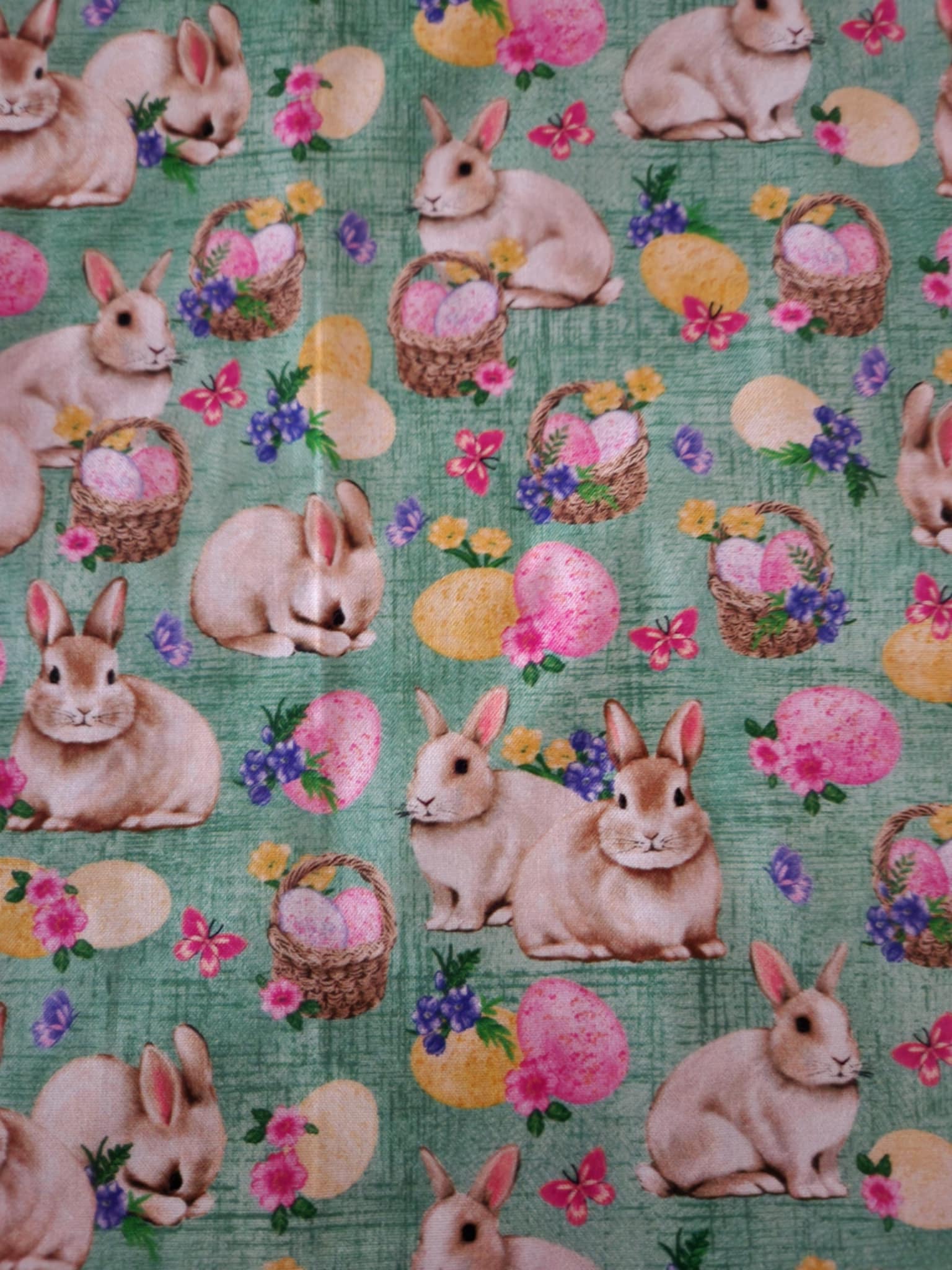 A close up table runner with bunnies' with baskets filled with Easter eggs in the middle.
