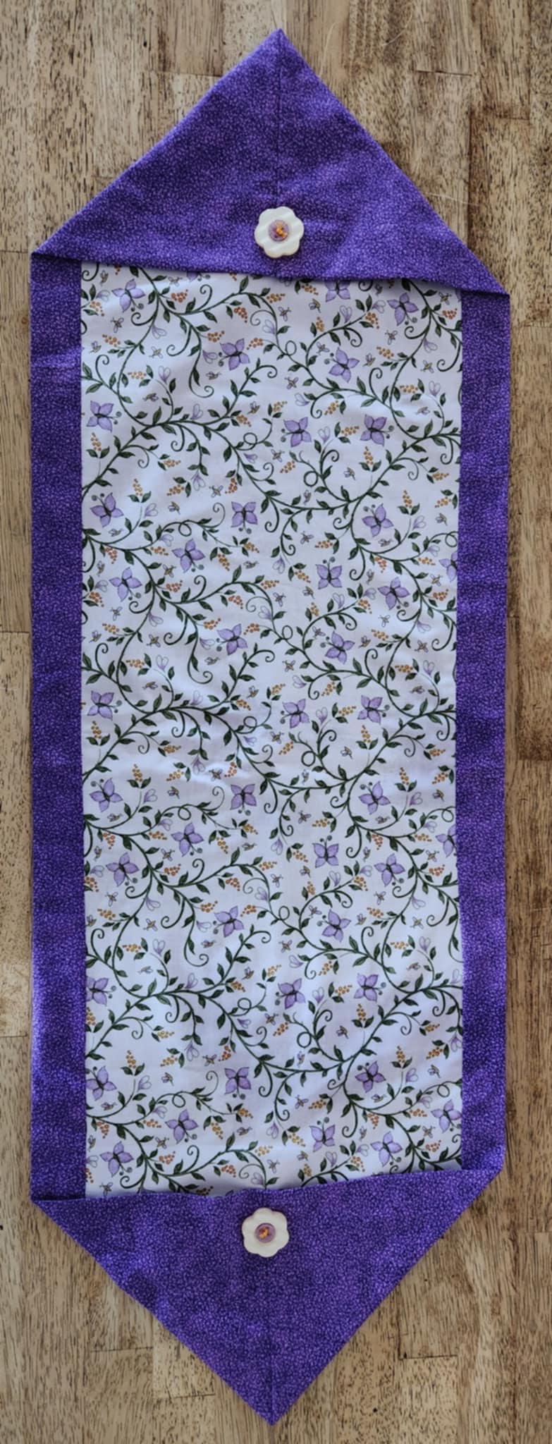 Top view table runner with butterfly's and flowers in the middle surrounded with a purple outside.