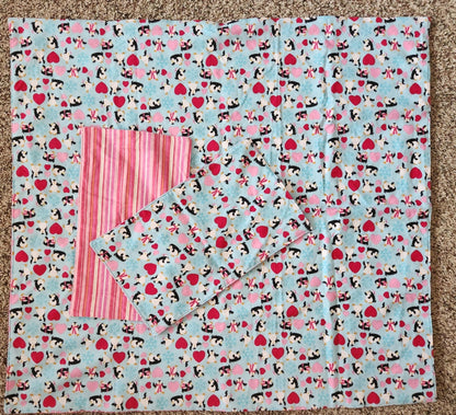 Square Receiving Blanket with Penguins, red and pink hearts with a blue background Fleece. With two burp rags made from the same fabric  with the backside with Red, pink and white Strips fabric on top of the blanket  