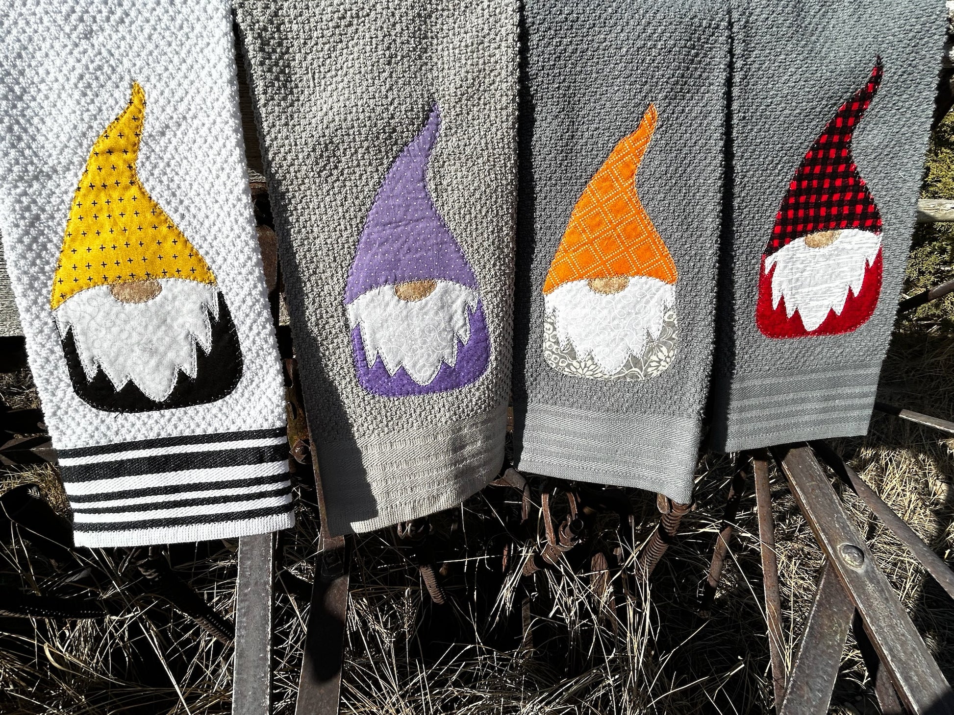 Four dish towels, three gray and one white. Each gnomes have a white beard but there top and bottom is a different color 