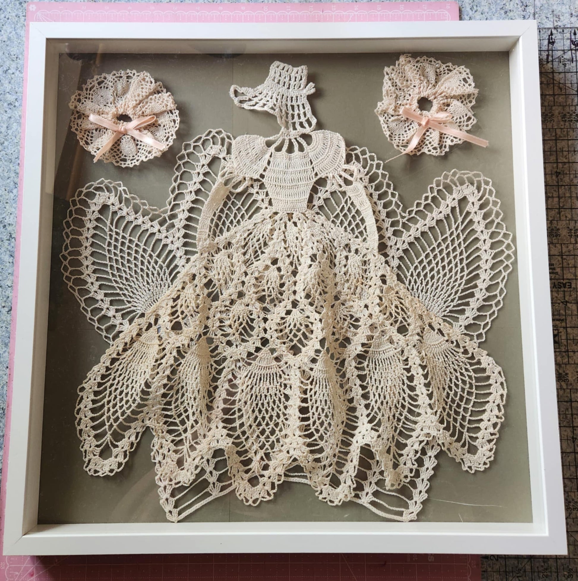A shadow box with white tatting thread made in to a ball gown and bonnet