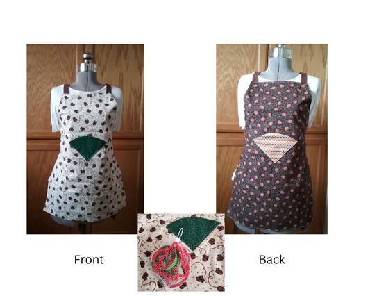 Front and back adult aprons, one with a polka dot pattern green pocket. With brown mittens on a white background. The apron is displayed frontally and the other backside showing the pocket with red, green, yellow and  and a blue squiggly lines. Main fabric has orange pumpkins on a brown background. Comes with cookie cutters. 