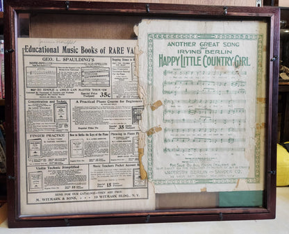 Wood shadow box with a sheet of music and a sheet about music. the sheet music is happy little country girl and the other is educational music books of rare....